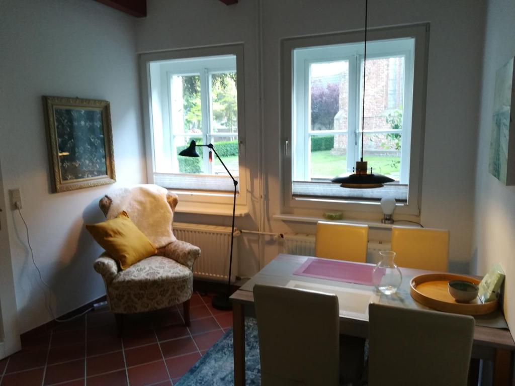 een woonkamer met een tafel, een stoel en ramen bij Ferienwohnung im historischen Zentrum 25562 in Weener