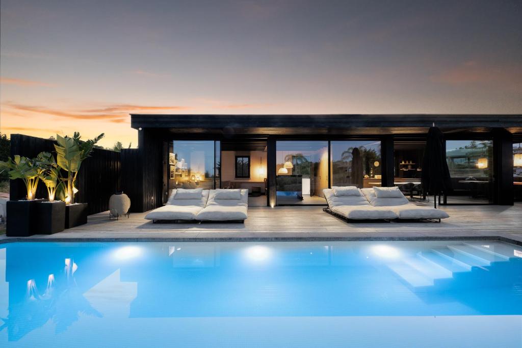 een huis met een zwembad met witte kussens bij Casa del Sol Estepona in Estepona