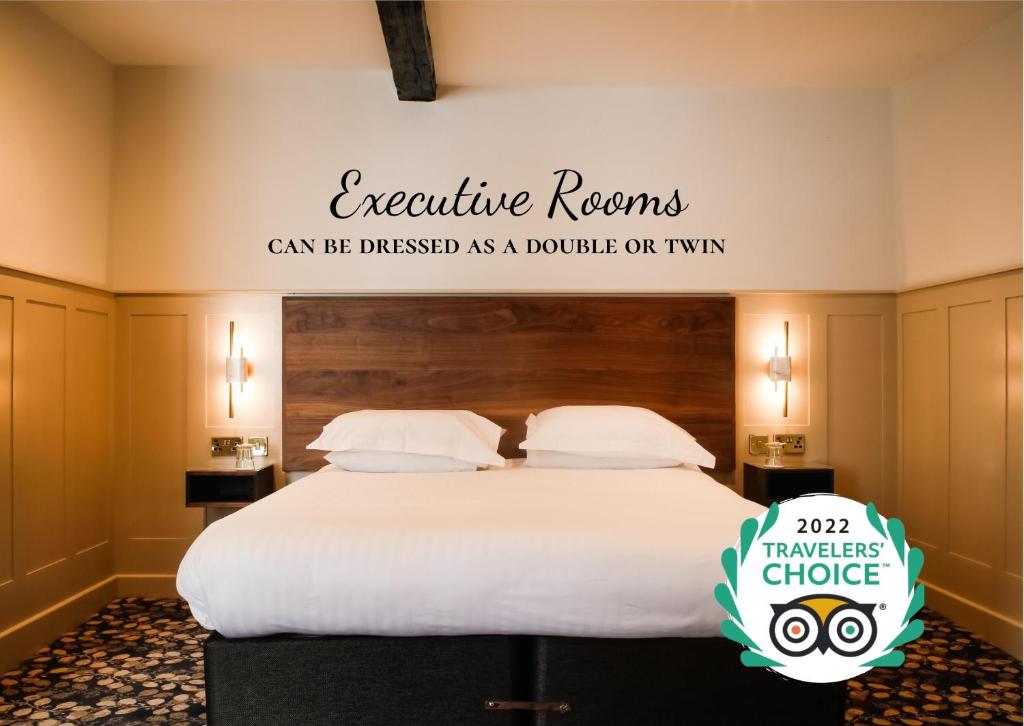 a bedroom with a bed with a sign that reads executive rooms can be distinguished as at Allerdale Court Hotel in Cockermouth