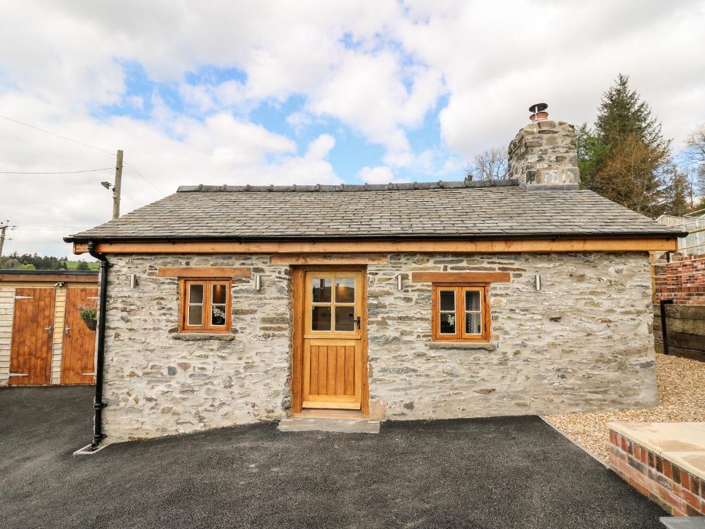 a small stone house with a wooden door at The Old Cobblers Shop in Llandrindod Wells