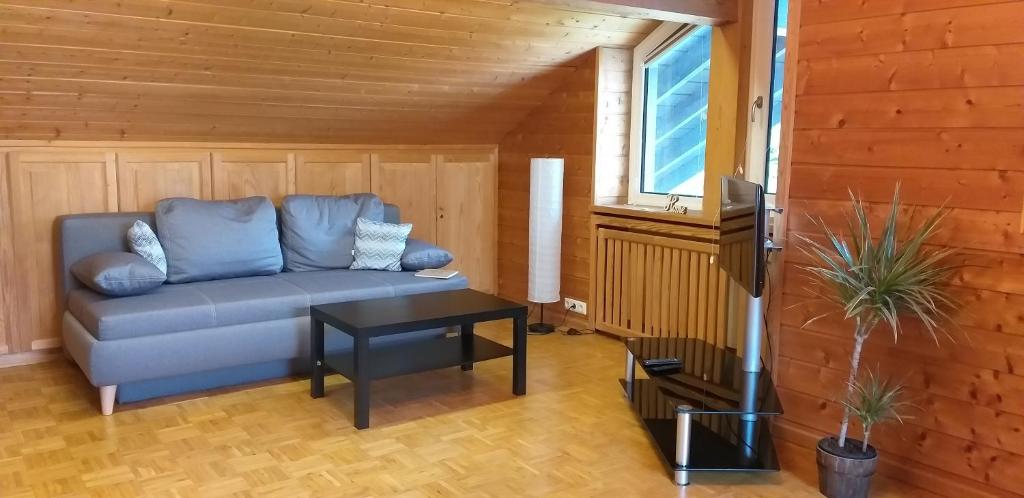 ein Wohnzimmer mit einem blauen Sofa und einem Tisch in der Unterkunft 2-Zimmer DG-Apartment mit eigener Sauna in Oberhaching