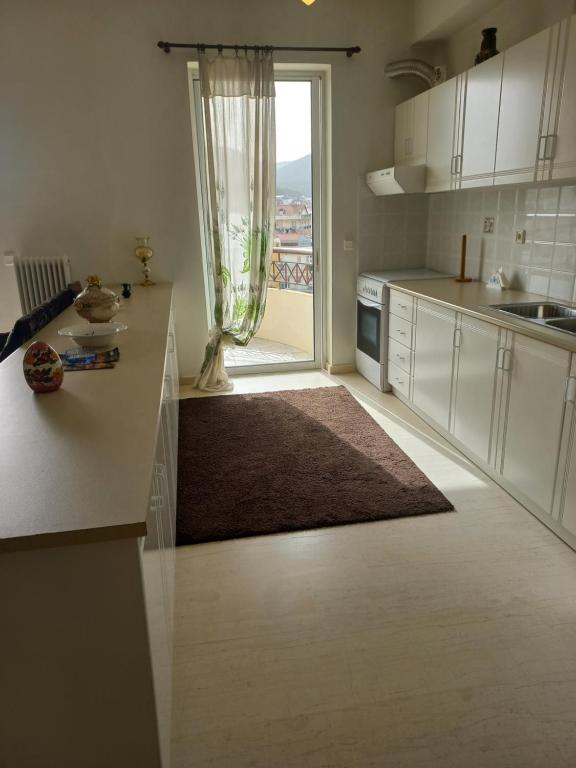eine Küche mit weißen Schränken und einem großen Fenster in der Unterkunft Great apartment with parking in the city center in Tripolis