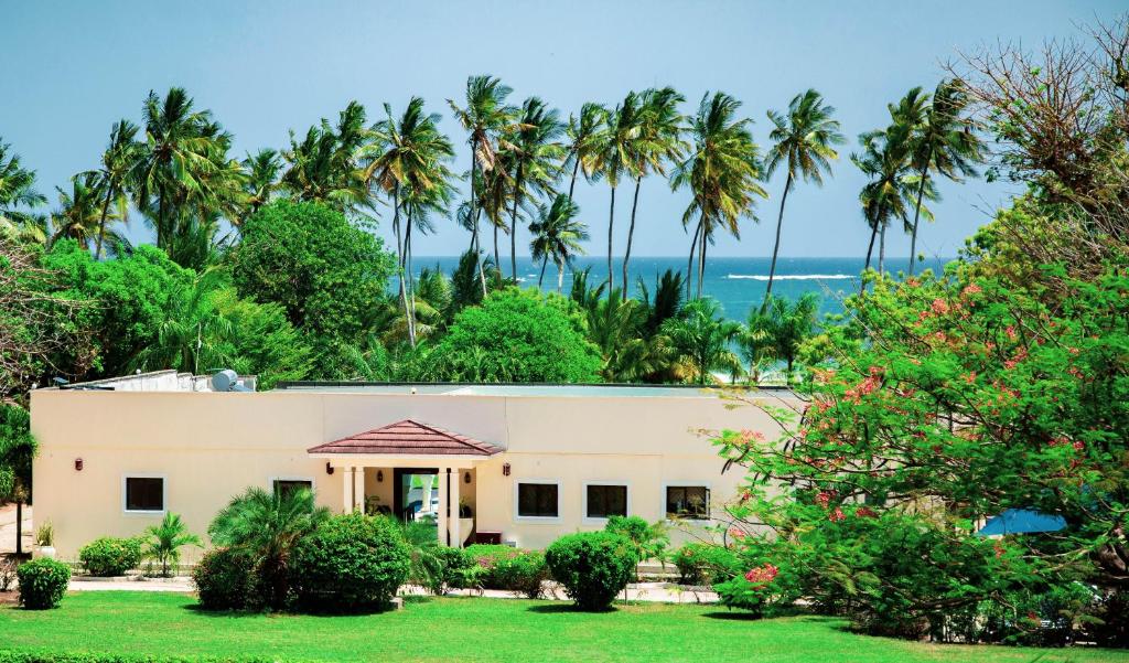 ein Haus mit Palmen und dem Meer im Hintergrund in der Unterkunft Mzima Beach Residences - Diani Beach in Diani Beach