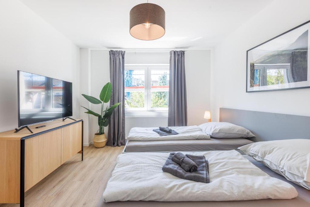 a bedroom with two beds and a flat screen tv at Glück Auf Appartements Schleiermacherstraße Duisburg in Duisburg