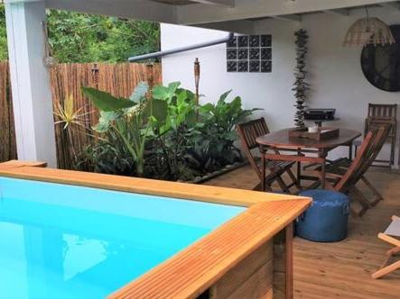 einen Pool auf einer Terrasse mit einem Tisch und Stühlen in der Unterkunft Cottage Tropical in L’Étang-Salé