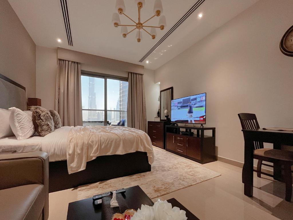 a bedroom with a bed and a flat screen tv at Studio Apartment with Sauna and Full Burj Khalifa View in Dubai