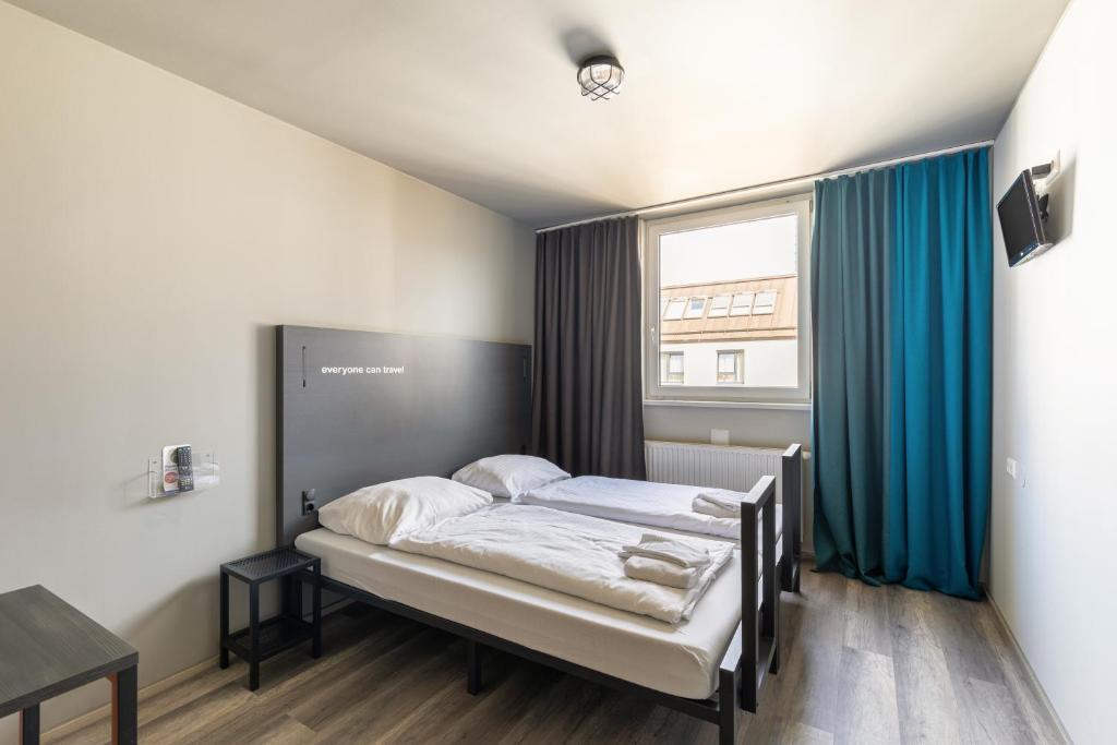 a bedroom with a bed with blue curtains and a window at a&o Wien Hauptbahnhof in Vienna
