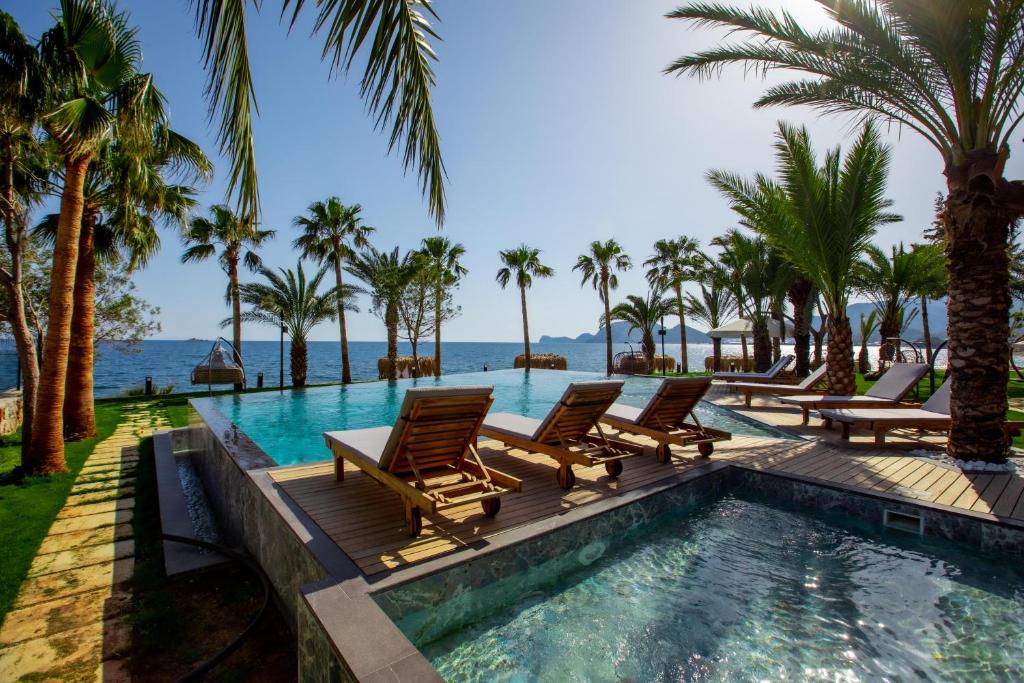 una piscina con tumbonas y palmeras en ELYSIUM GARDEN HOTEL, en Bozyazı