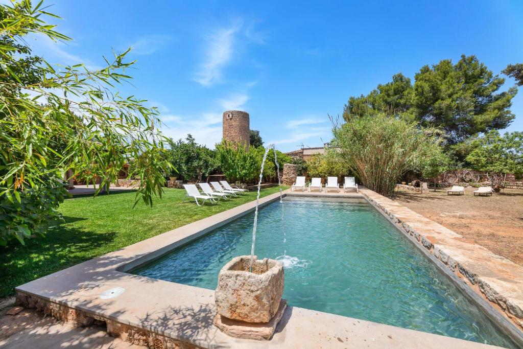 a swimming pool with a fountain in a yard at Can Estela in Sencelles