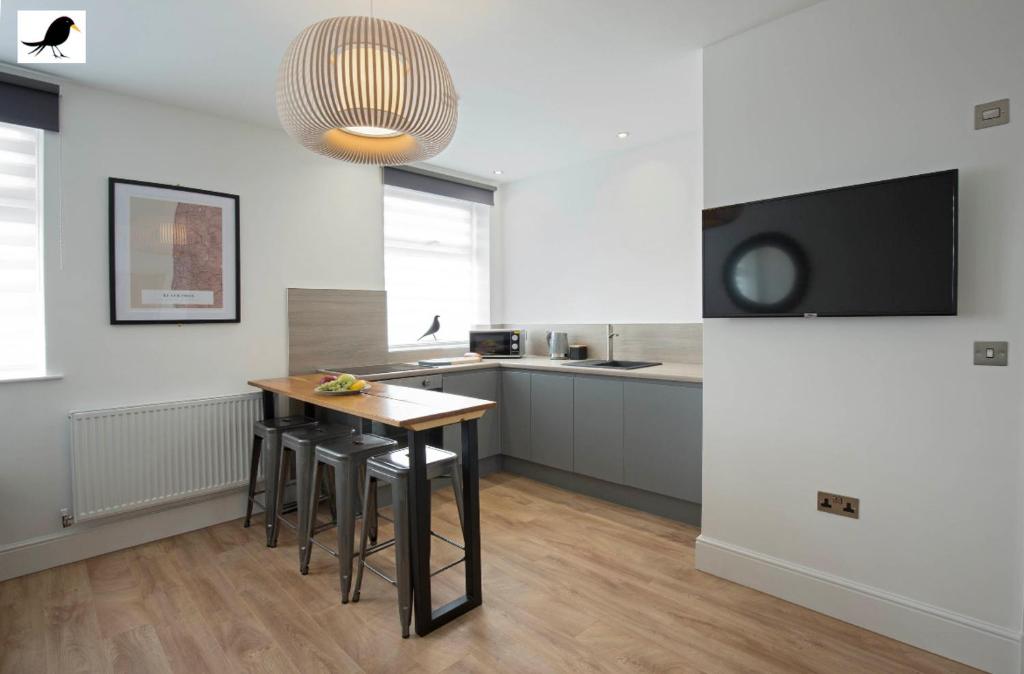 eine Küche mit einem Tisch und einigen Hockern in einem Zimmer in der Unterkunft Blackbird Accommodation and Luxury Apartments room 15 in Blackpool