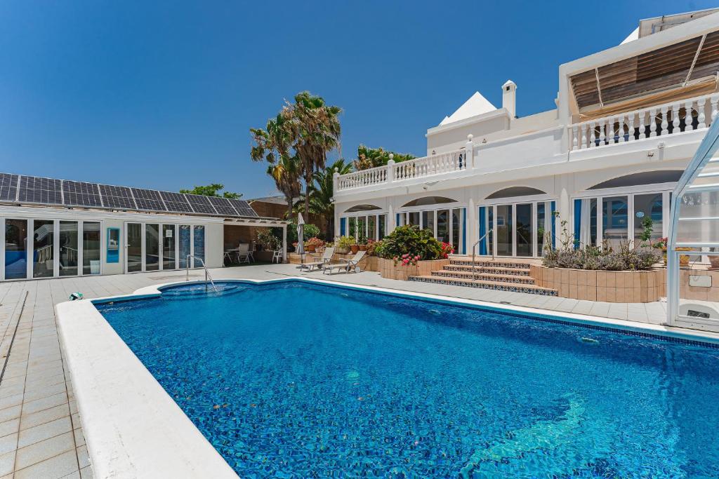 a large house with a swimming pool in front of it at Gorgeous Golf Villa Heated Pool Sea view in Adeje