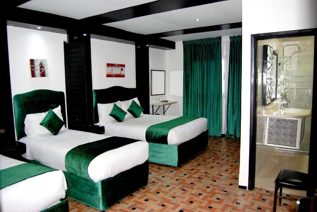 two beds in a room with green and white at Hotel Al Khaima in Asilah