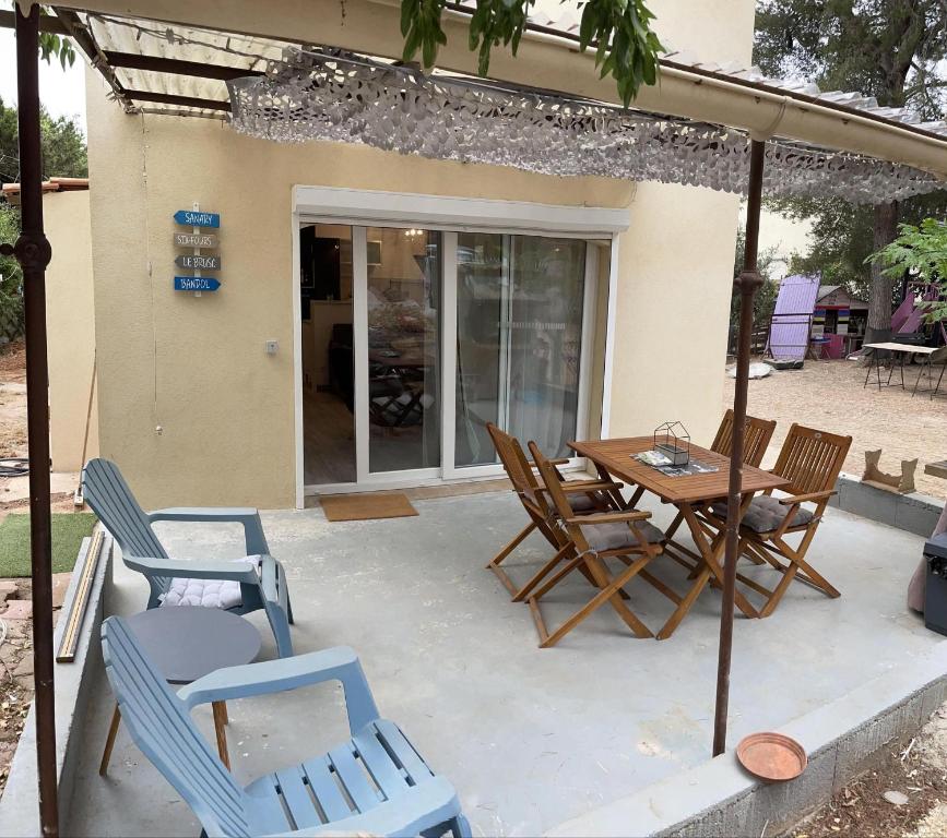 une terrasse avec des chaises, une table et un parasol dans l'établissement Mas Eugenie agrandie et rénovée, à Six-Fours-les-Plages