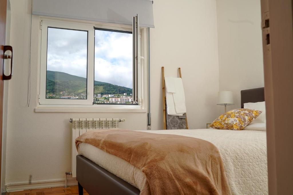 ein Schlafzimmer mit einem Bett und einem großen Fenster in der Unterkunft Casa Origens in Seia