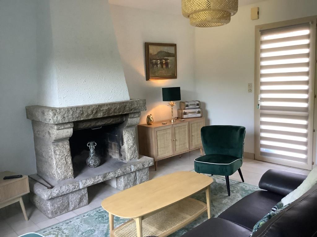 sala de estar con chimenea de piedra y silla verde en Gîte Maez 4 pers 29450 sizun, en Sizun
