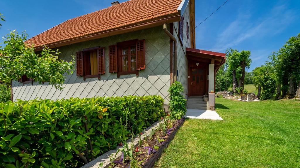 una piccola casa con una siepe verde davanti di Kuća za odmor Feniks 3 a Ravna Gora
