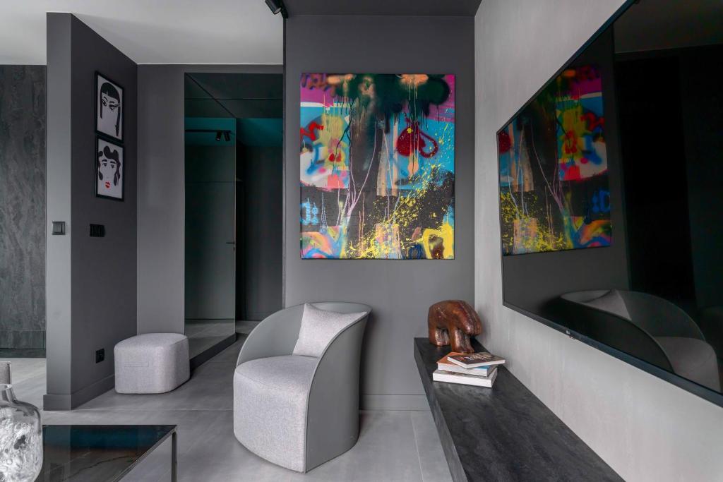 een woonkamer met een stoel en schilderijen aan de muur bij Niegaleria Apartament in Wrocław
