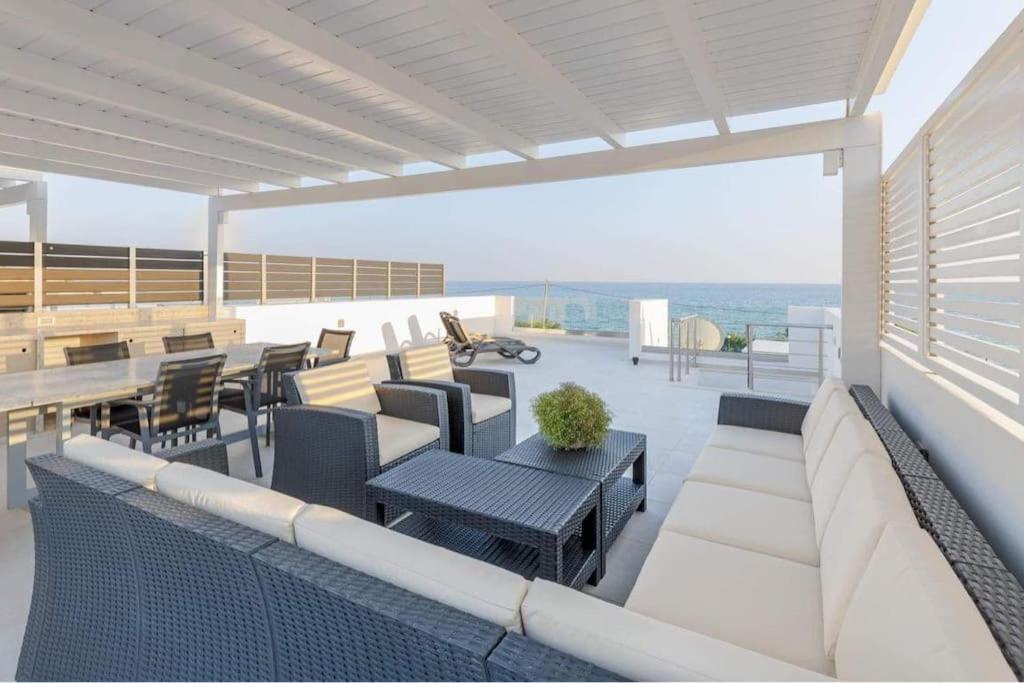 a patio with a couch and tables and chairs at Makrigialos Long Beach Villas - Penthouse 1 in Makry Gialos