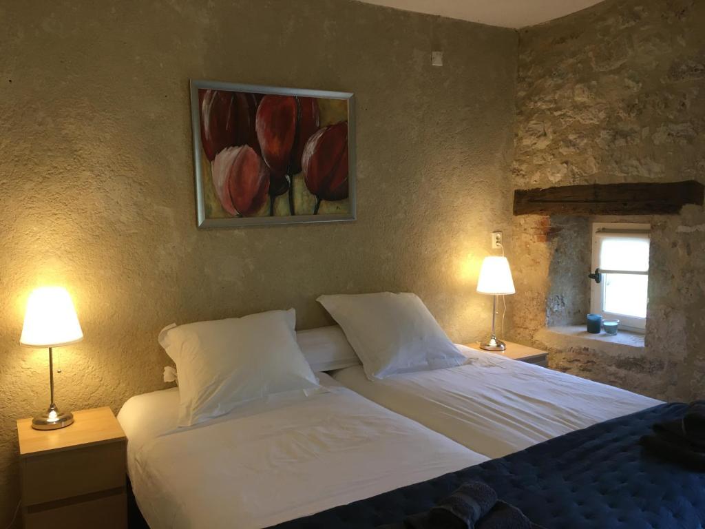 a bedroom with two beds and two lamps and a painting at Les Gonies - Cyprès in Mauroux