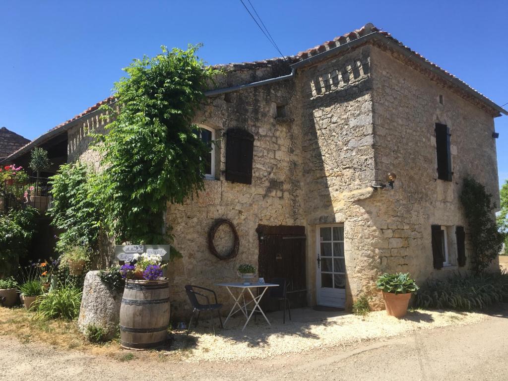 una vieja casa de piedra con una mesa delante en Les Gonies - Amande, en Mauroux