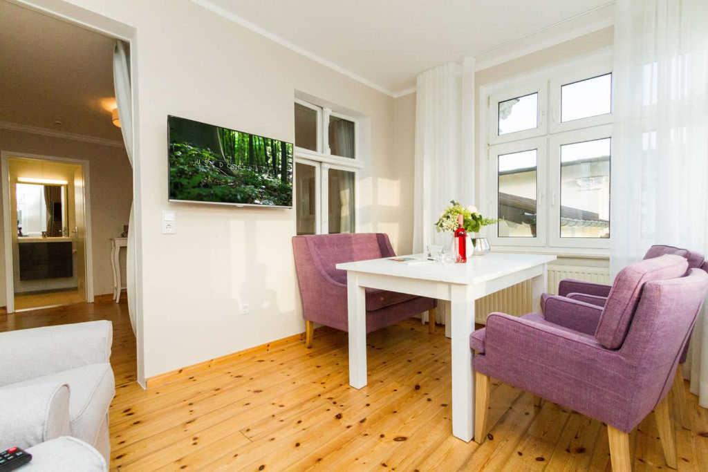 uma sala de estar com uma mesa e duas cadeiras roxas em Villa Albertine App 08 em Ahlbeck