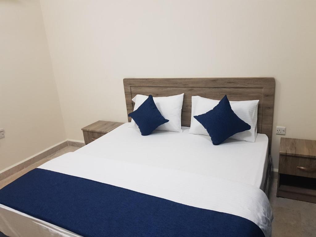 a bedroom with a white bed with blue pillows at Today House Suites 2 in Salalah