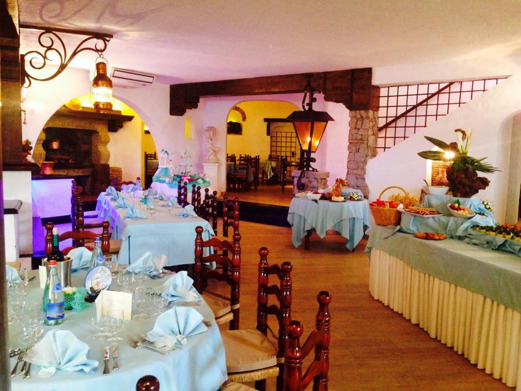 jadalnia z białymi stołami i krzesłami w pokoju w obiekcie Hotel Cala di Mola w mieście Porto Azzurro