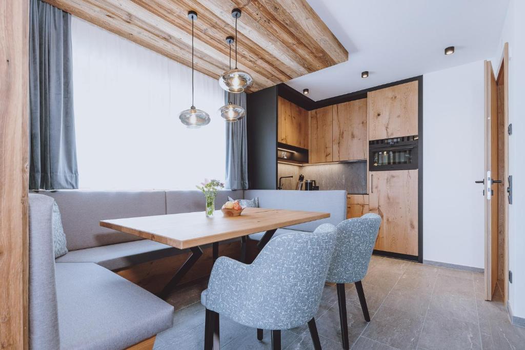 a kitchen and dining room with a wooden table and chairs at Bergdorf Hotel Zaglgut in Kaprun