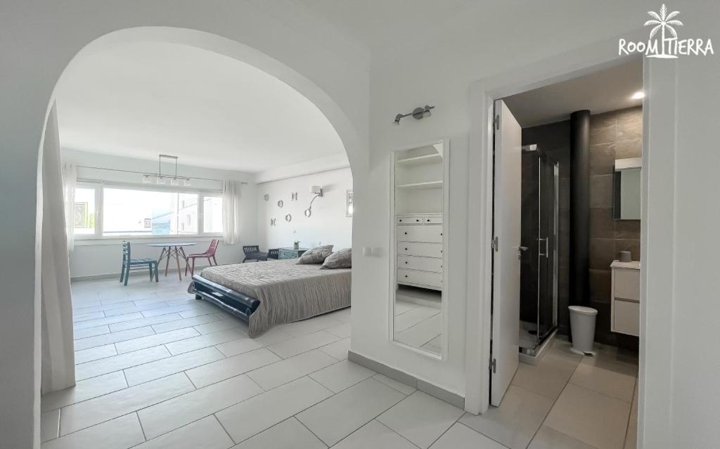 a white bedroom with a bed and a table at Room Tierra wifi free private bathroom , central town in Corralejo