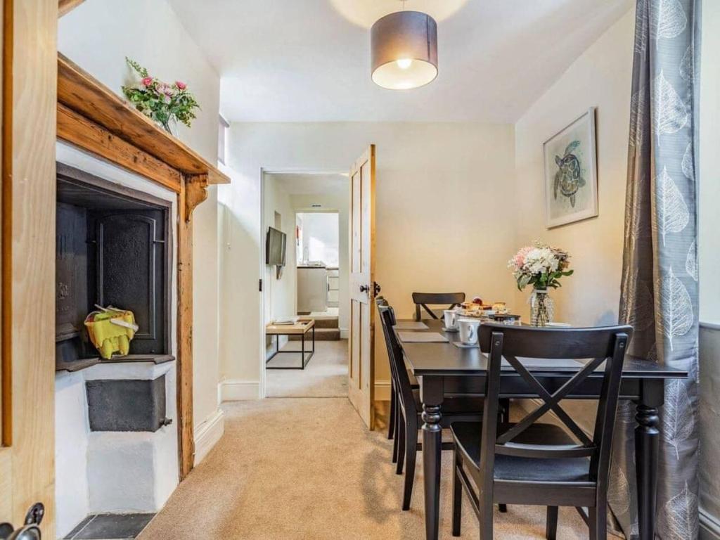 a dining room with a table and chairs and a fireplace at Lovely Stunning 2-Bed Cottage in Torquay in Torquay