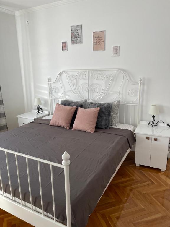 a white bed with pink pillows in a bedroom at Apartment Cactus 021 in Novi Sad