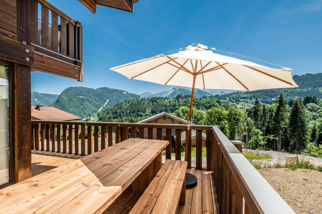 drewniany taras z ławką i parasolem w obiekcie Chalet Cipolin Morzine - by EMERALD STAY w mieście La Côte dʼArbroz