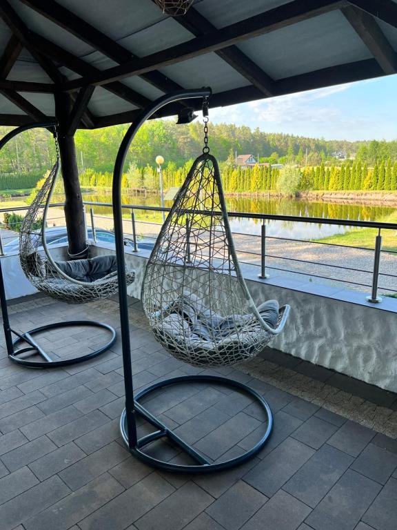two hanging hammocks on a patio near a river at Rybaczówka Golub-Dobrzyń in Golub-Dobrzyń