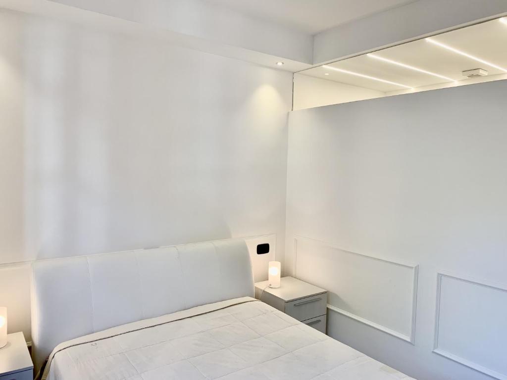 een witte slaapkamer met een bed en twee kaarsen bij Lerici WhiteHouse in Lerici