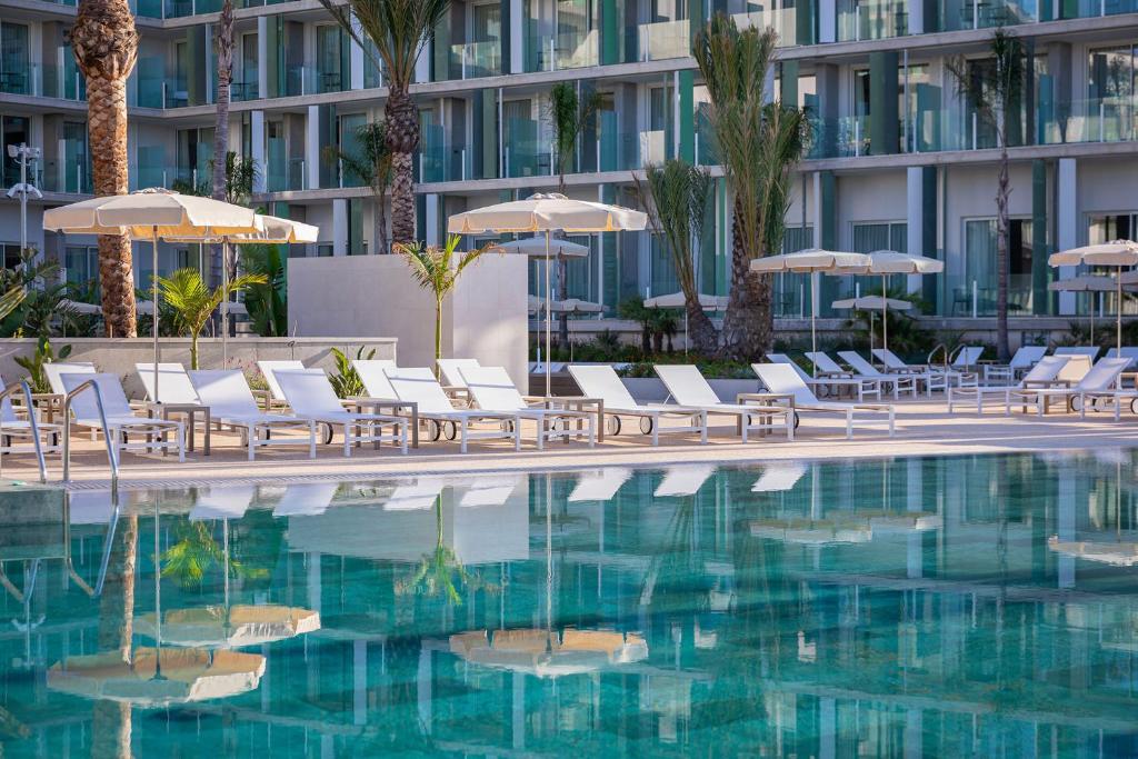 einen Pool mit Stühlen und Sonnenschirmen neben einem Gebäude in der Unterkunft Atzavara Hotel & Spa in Santa Susanna