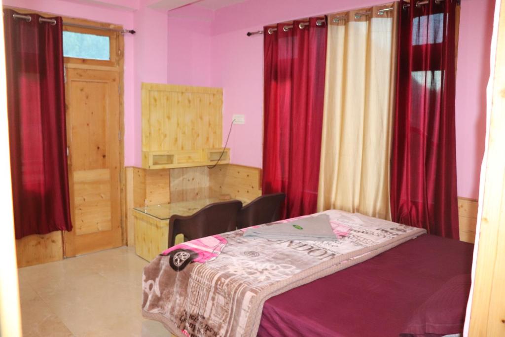 ein kleines Zimmer mit einem Tisch und roten Vorhängen in der Unterkunft Shesh Besh Guest House & Restaurant in Kasol