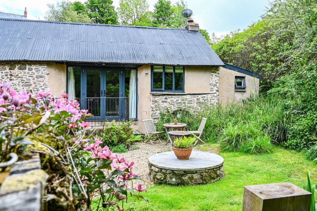 a stone cottage with a table and chairs in a yard at The Bothy - a cosy little rustic barn in Parracombe