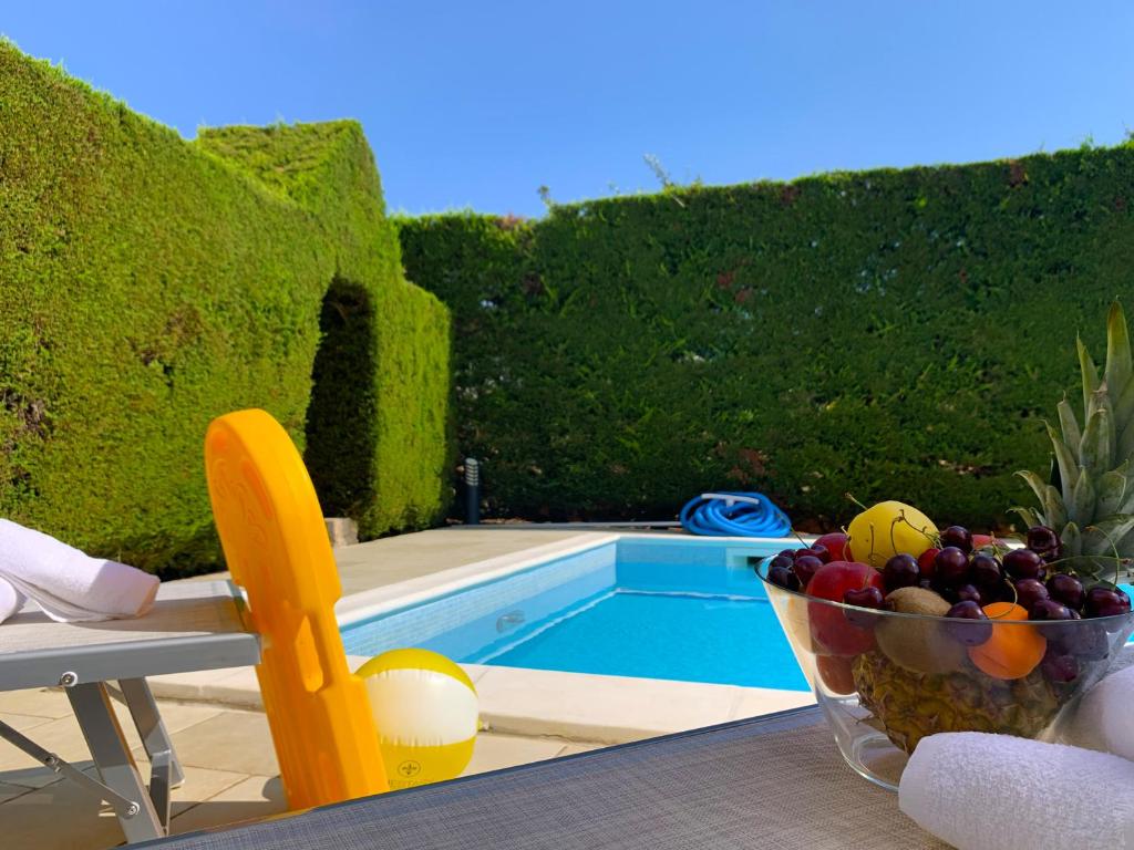 a bowl of fruit sitting on a table next to a pool at Villa parco la Ruta, Piscina e relax in Noci