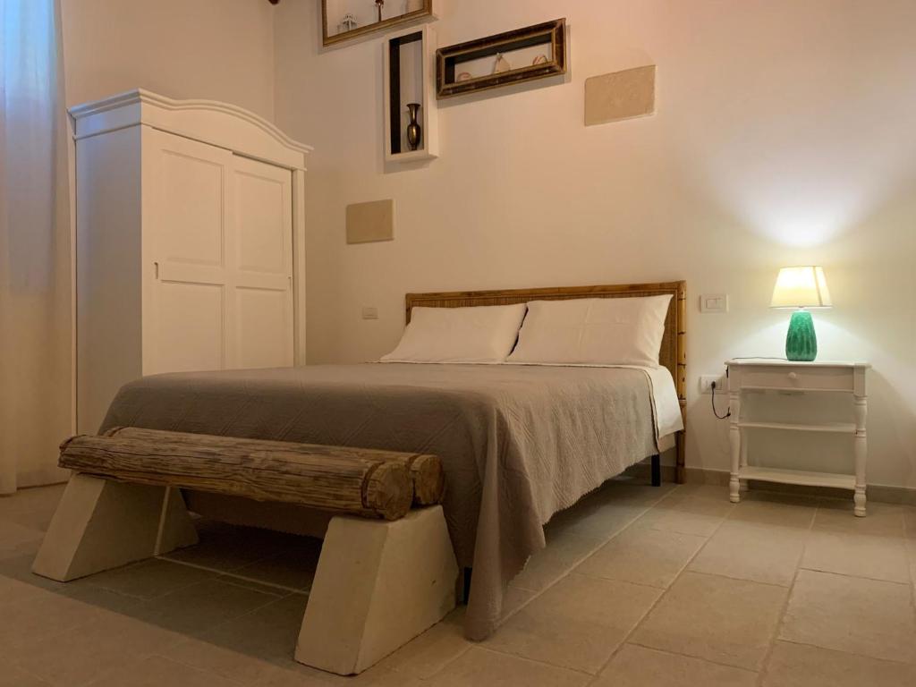 Dormitorio con cama con banco y lámpara en Masseria Petra, en Martano