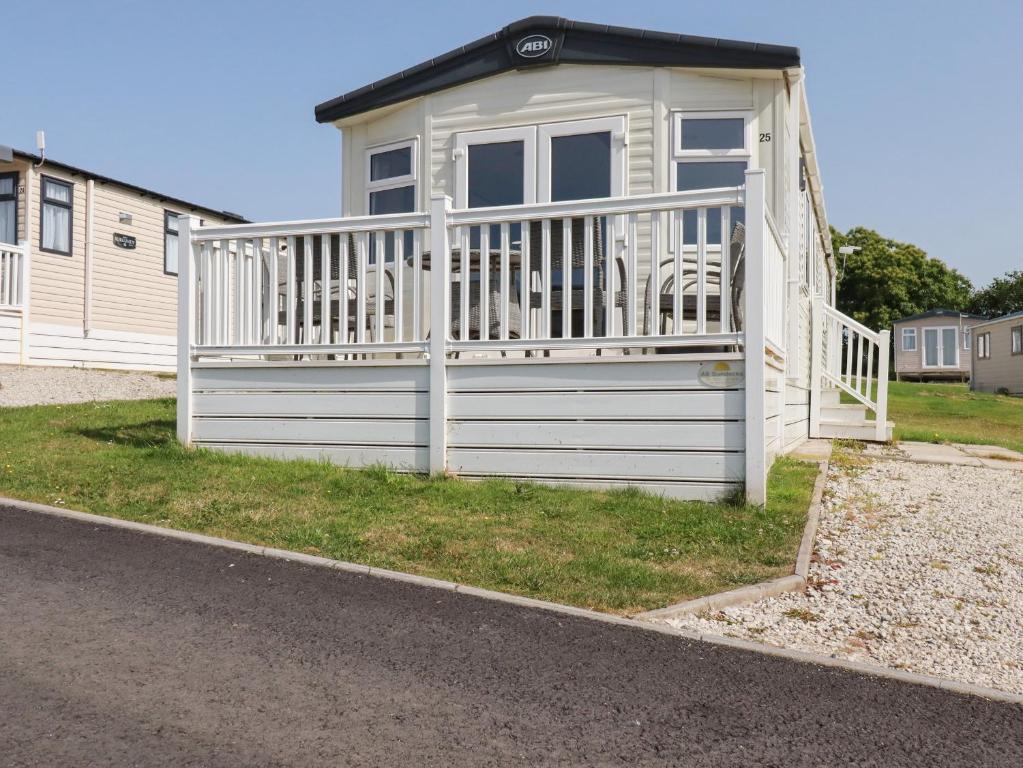 een klein huis met een wit hek en stoelen bij Finch 25 - Meadow Lakes Holiday Park in St Austell