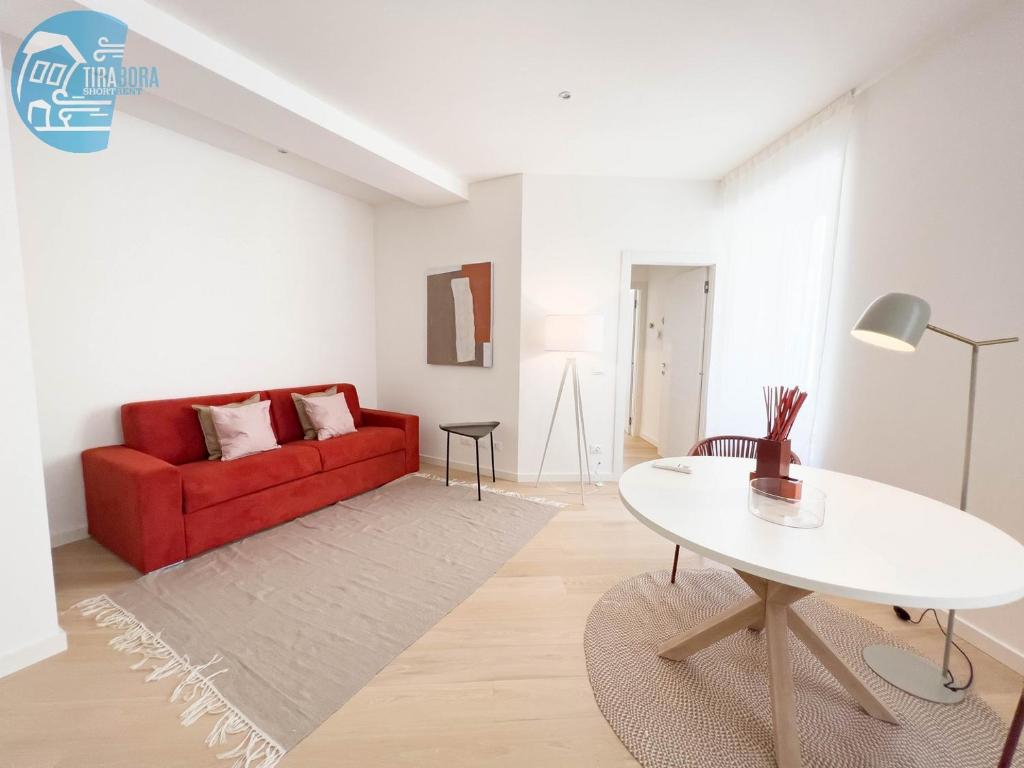 sala de estar con sofá rojo y mesa blanca en Slataper 12 Tirabora Short Rent, en Trieste