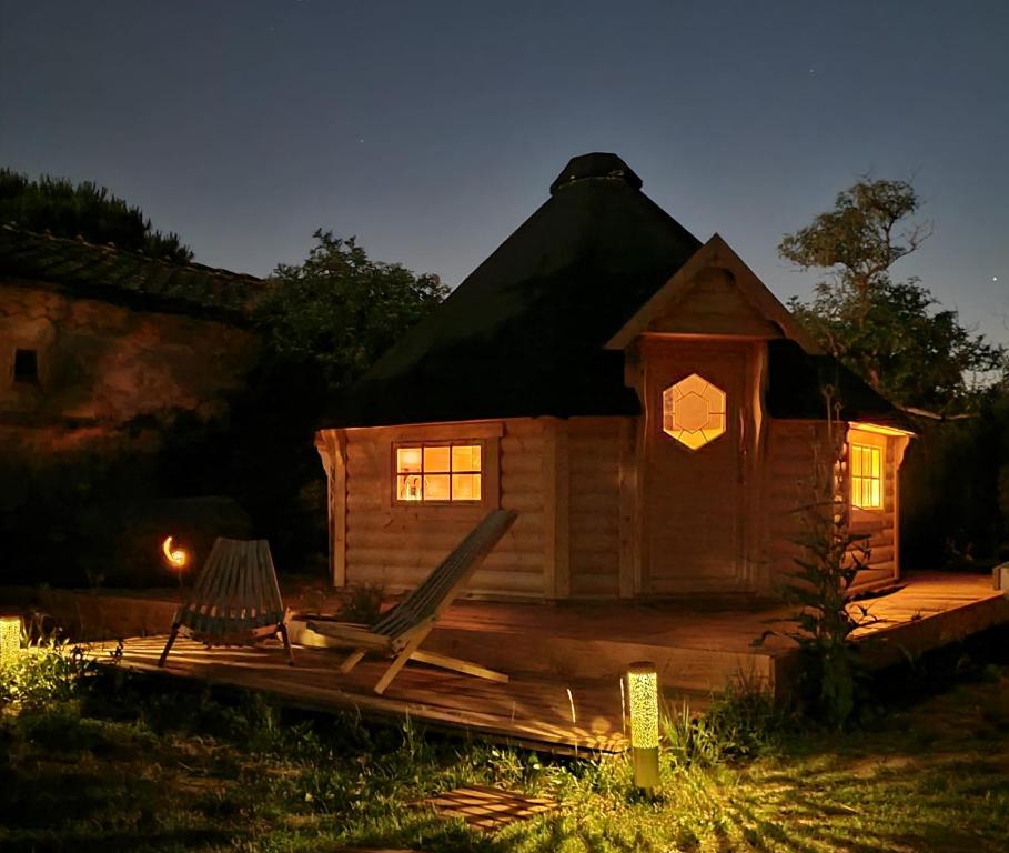 una cabaña de madera con un banco y una silla frente a ella en Les Etoiles de Morphée en Auriac-sur-Vendinelle