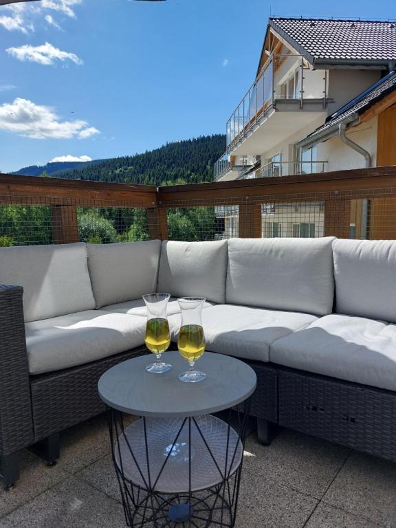 twee glazen wijn zittend op een bank op een patio bij Apartament Sienna Czarna Góra STUBAI 5 in Siena