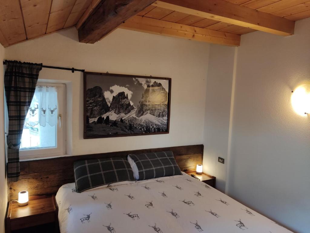 una camera da letto con un letto e un dipinto sul muro di Cèsa Viosadea a Campitello di Fassa