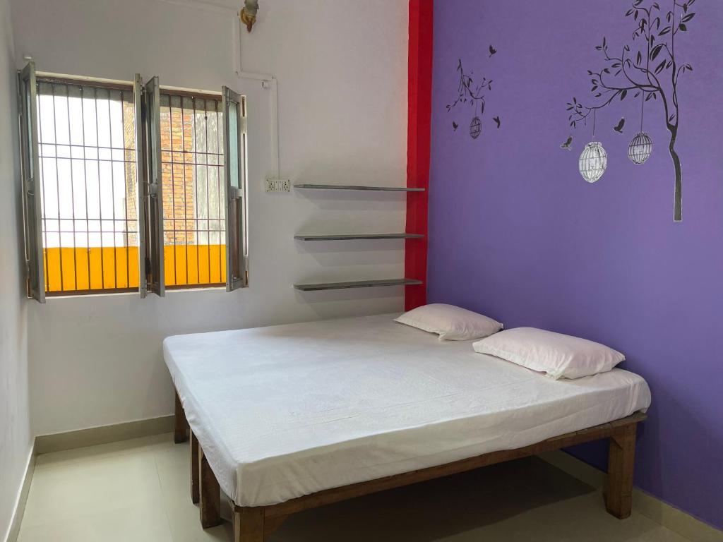 Cama pequeña en habitación con paredes moradas en Indra Paying Guest House en Varanasi
