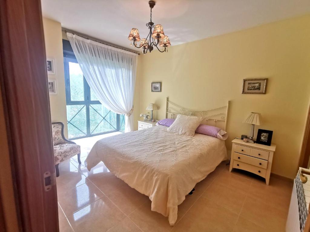 una camera con letto, finestra e lampadario a braccio di Apartamento de 3 dormitorios con piscina - Riaza Vacacional a Riaza
