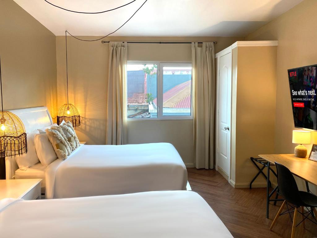 a hotel room with two beds and a window at Magnolia Inn in Panama City
