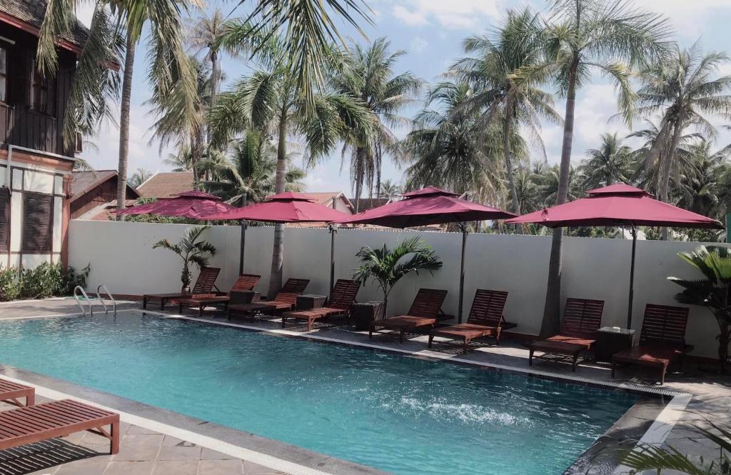 a swimming pool with chairs and umbrellas at Villa Mahasok hotel in Luang Prabang
