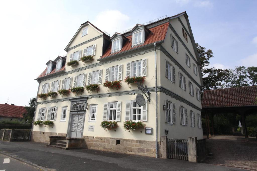 ein weißes Gebäude mit Blumenkästen an den Fenstern in der Unterkunft Poststation Zum Alten Forstamt in Morschen