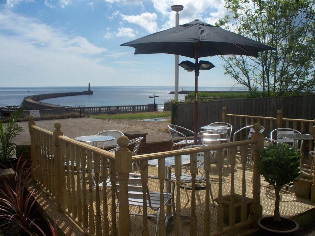 uma mesa e cadeiras com um guarda-sol num deque em The Balmoral & Terrace Guest Houses em Sunderland